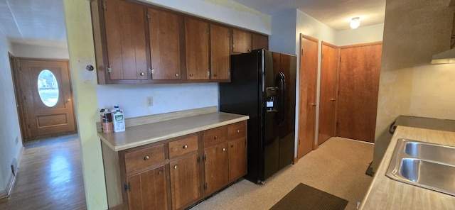 kitchen with light countertops, black refrigerator with ice dispenser, and a sink