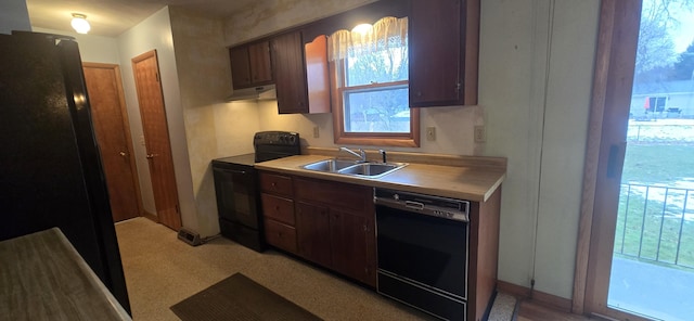 kitchen featuring black appliances, under cabinet range hood, light countertops, and a sink