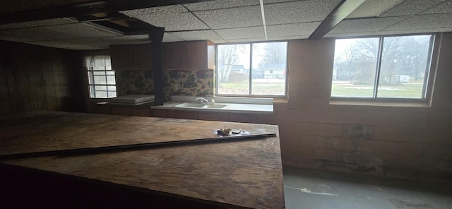 interior space featuring a paneled ceiling, a sink, and concrete block wall