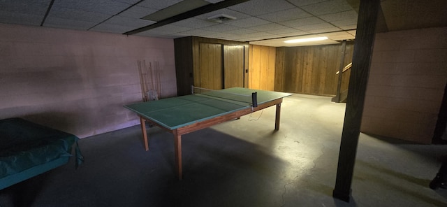 game room featuring concrete flooring, a paneled ceiling, visible vents, and wood walls