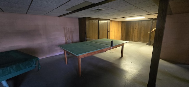 playroom with a paneled ceiling, concrete floors, visible vents, and concrete block wall