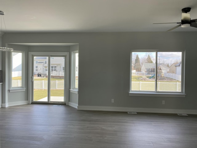 empty room with plenty of natural light, wood finished floors, and baseboards