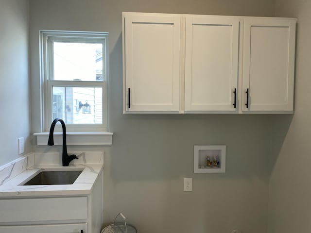 washroom with hookup for a washing machine, cabinet space, and a sink