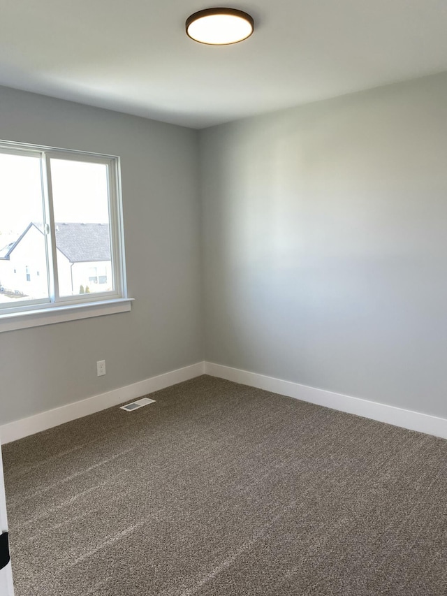 carpeted spare room featuring visible vents and baseboards