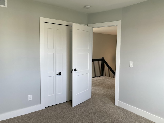 unfurnished bedroom with carpet floors, a closet, visible vents, and baseboards