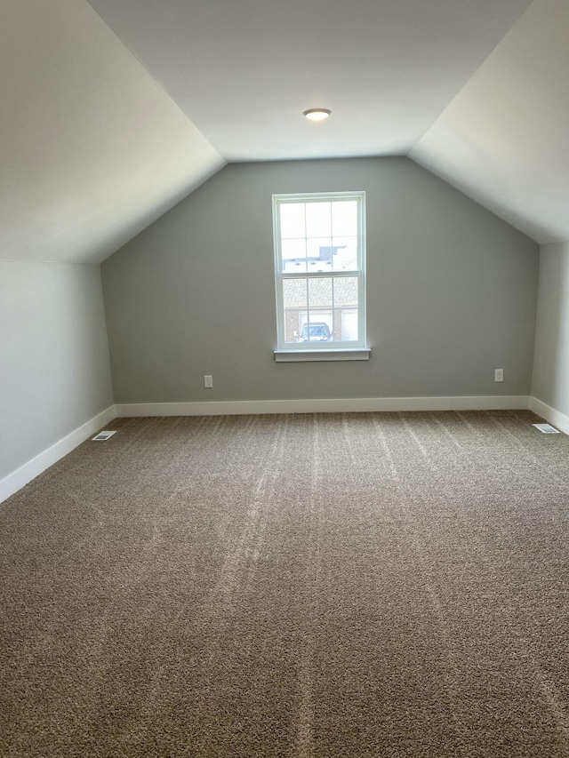 bonus room featuring carpet floors, visible vents, vaulted ceiling, and baseboards