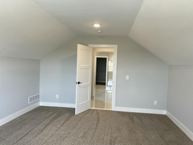 bonus room featuring lofted ceiling, dark colored carpet, and visible vents