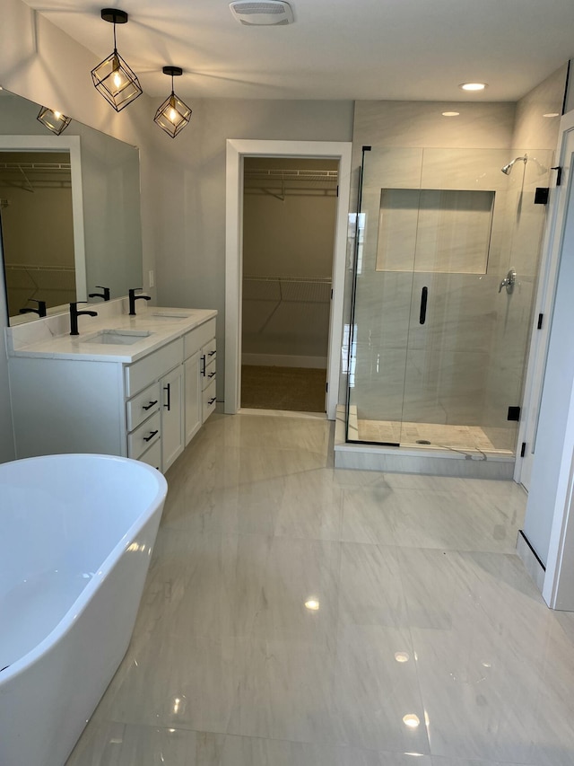 bathroom featuring a sink, a freestanding bath, a shower stall, double vanity, and a walk in closet