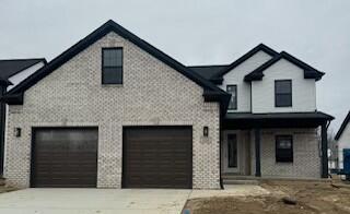 view of front of house with a garage, concrete driveway, and brick siding