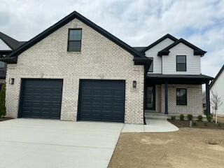 view of front of home featuring driveway, covered porch, brick siding, and a garage