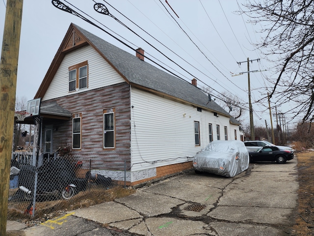 2124 E Forest Ave, Detroit, MI 48207 - view of side of property with a chimney, fence, and roof with shingles