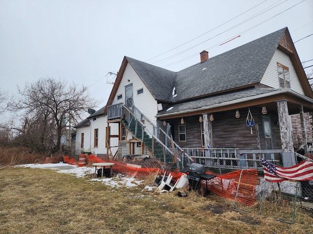2124 E Forest Ave, Detroit, MI 48207 - rear view of house featuring a chimney, stairs, a porch, a shingled roof, and a lawn