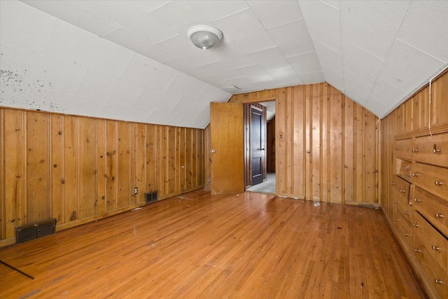 bonus room featuring vaulted ceiling, wood walls, wood finished floors, and visible vents