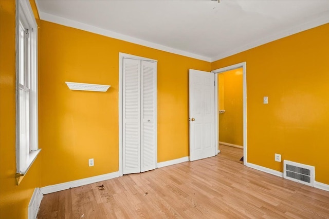 unfurnished bedroom with a closet, baseboards, visible vents, and light wood finished floors