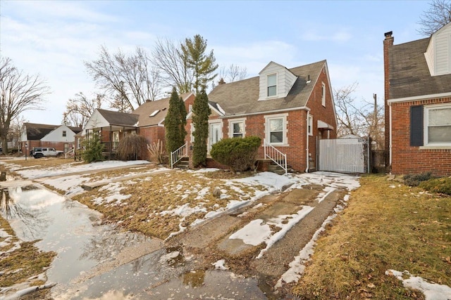 cape cod-style house with a residential view, a gate, brick siding, and fence