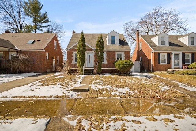 new england style home featuring a residential view and brick siding