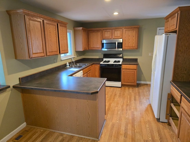 kitchen featuring gas range oven, a sink, freestanding refrigerator, stainless steel microwave, and dark countertops