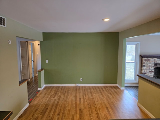 unfurnished living room with a fireplace, wood finished floors, and baseboards