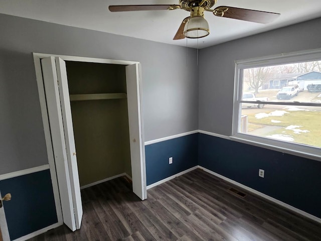 unfurnished bedroom featuring visible vents, a closet, baseboards, and dark wood-style flooring