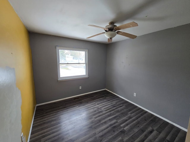 spare room with baseboards, visible vents, dark wood finished floors, and a ceiling fan