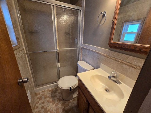 bathroom with toilet, a shower stall, tile walls, and vanity