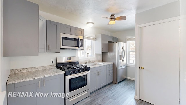 kitchen featuring a sink, stainless steel appliances, gray cabinets, and light countertops