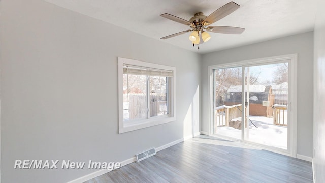 spare room featuring wood finished floors, a wealth of natural light, and baseboards