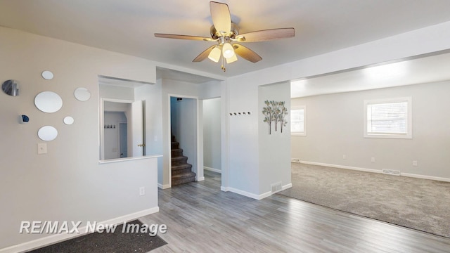 empty room featuring stairs, light wood-type flooring, and baseboards