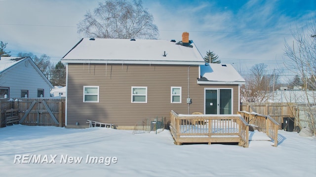 snow covered rear of property featuring fence and a deck