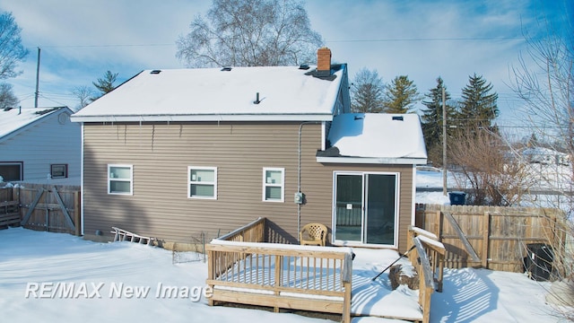 snow covered back of property with fence and a wooden deck