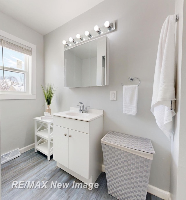 bathroom with wood finished floors, vanity, visible vents, and baseboards