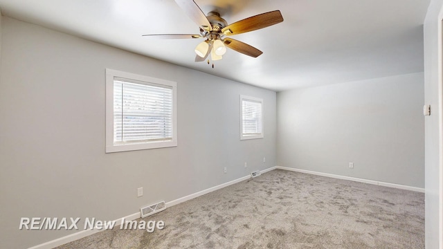 carpeted empty room featuring ceiling fan, visible vents, and baseboards