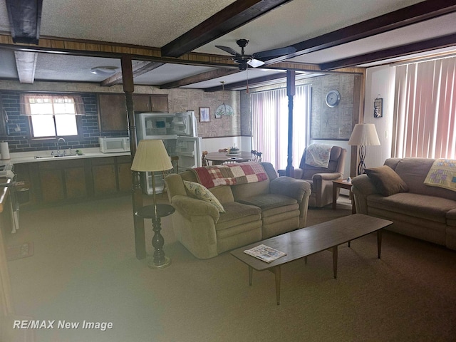 living area featuring beamed ceiling and a ceiling fan