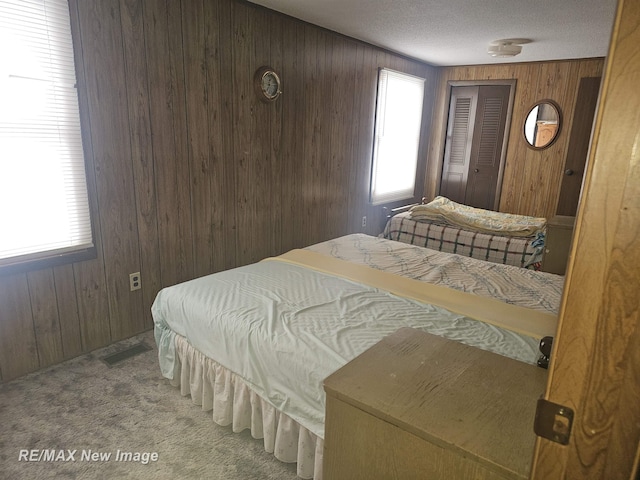 bedroom with carpet floors, wood walls, and a textured ceiling