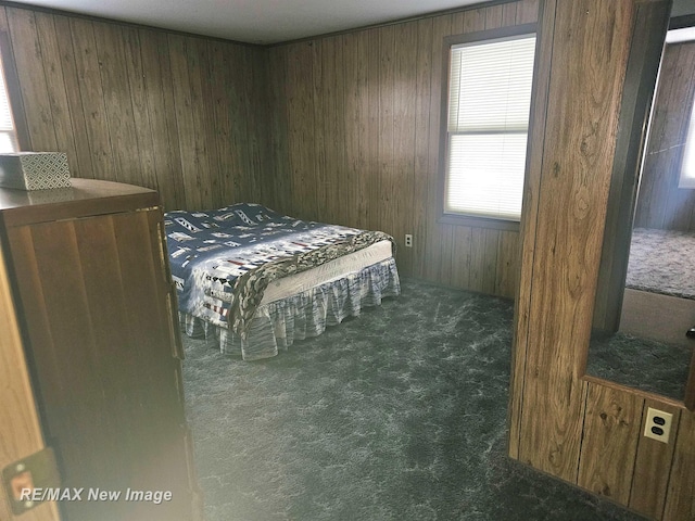 bedroom with dark carpet and wooden walls