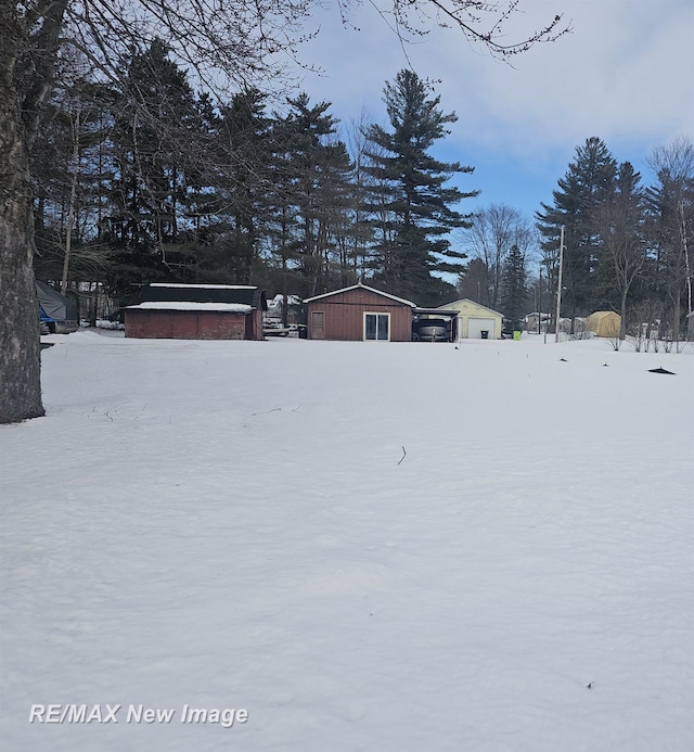 snowy yard with a garage and an outdoor structure