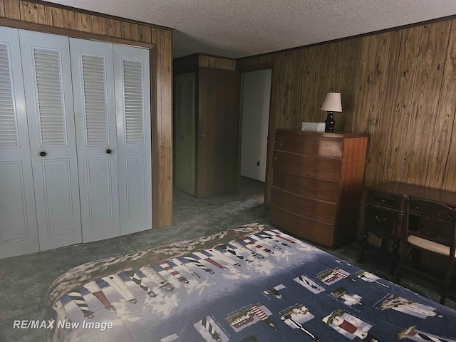 bedroom with a closet, wooden walls, dark carpet, and a textured ceiling