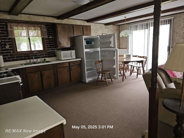 5243 Martin Rd, Beaverton, MI 48612 - kitchen featuring white microwave, light countertops, carpet floors, gas stove, and beam ceiling