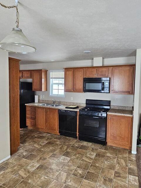 kitchen with black appliances, baseboards, brown cabinets, and a sink