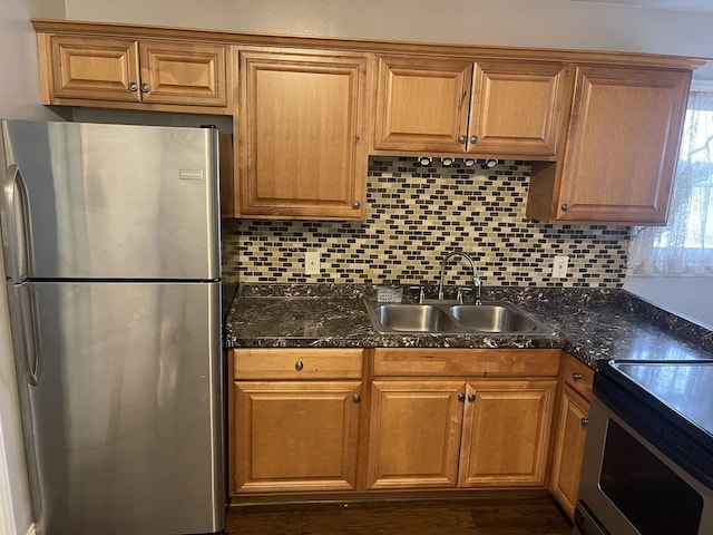 kitchen with stainless steel appliances, dark countertops, a sink, and tasteful backsplash