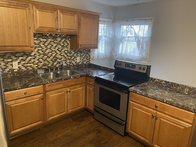 kitchen with dark wood-style flooring, dark countertops, decorative backsplash, stainless steel range with electric cooktop, and a sink