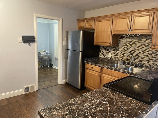 kitchen with brown cabinets, freestanding refrigerator, visible vents, and a sink