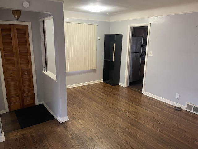 spare room featuring baseboards, visible vents, and dark wood finished floors