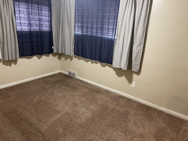 carpeted spare room featuring baseboards and visible vents