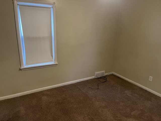 unfurnished room with carpet floors, visible vents, and baseboards