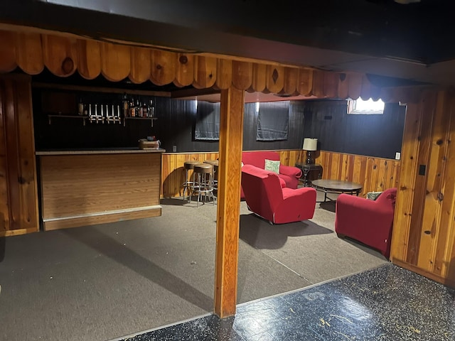 finished basement featuring wainscoting, wooden walls, and a bar