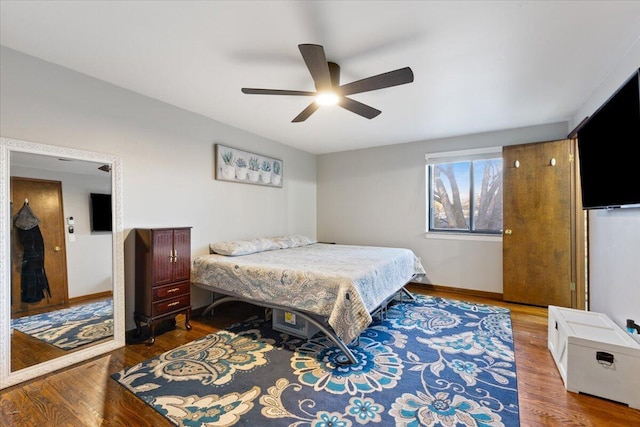 bedroom with a ceiling fan, baseboards, and wood finished floors