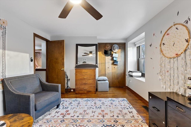 sitting room with baseboards, ceiling fan, visible vents, and wood finished floors