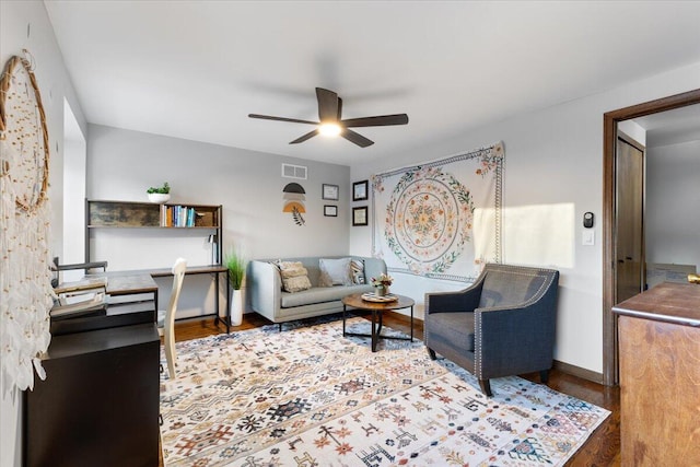 living area with ceiling fan, dark wood-type flooring, visible vents, and baseboards