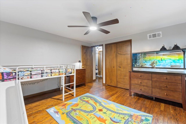 bedroom with dark wood-style floors, a closet, visible vents, and a ceiling fan